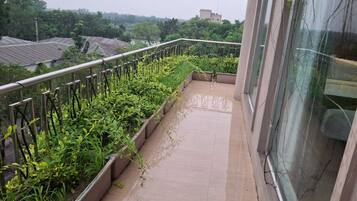 A balcony with a metal railing, potted plants, and a tiled floor.