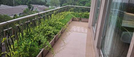 A balcony with a metal railing, potted plants, and a tiled floor.