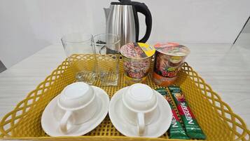 Una bandeja con dos tazas blancas, dos vasos, una tetera y dos recipientes de café instantáneo.