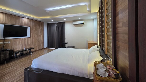 Une chambre d’hôtel avec un grand lit, un téléviseur à écran plat fixé au mur, un bureau et une chaise.