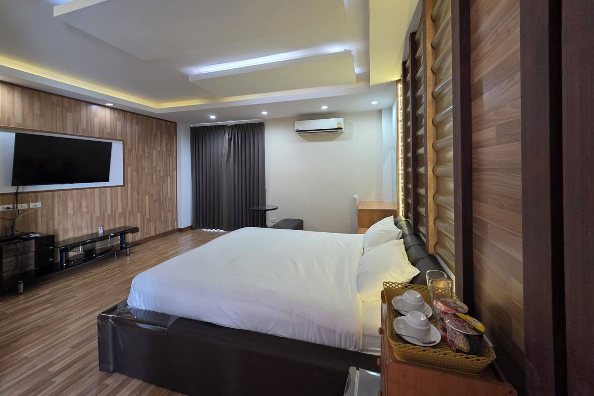 Ein Hotelzimmer mit einem großen Bett, einem an der Wand befestigten Flachbildfernseher, einem Schreibtisch und einem Sessel.