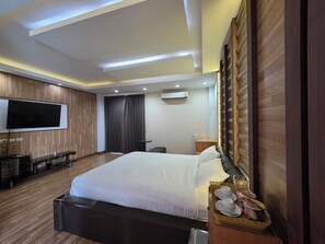 A hotel room with a large bed, a flat-screen TV mounted on the wall, a desk, and a chair. - O-Haus Chiangmai Airbnb Host (Hang Dong)