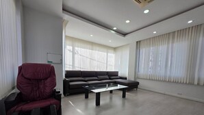 Un salon moderne avec un canapé d’angle, une table basse en verre et un fauteuil rouge.