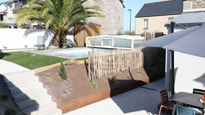A residential backyard with a swimming pool, a wooden deck, a covered patio, and a staircase leading to a house. - Azur Cancale (Cancale)