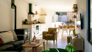A compact living space with a sofa, a dining table with chairs, a kitchen area, and a large window providing natural light. - Azur Cancale (Cancale)
