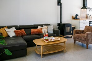 Ein Wohnzimmer mit Sofa, Couchtisch, Sessel, Kamin und einer Küchenzeile.