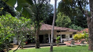 A house with a tiled roof, surrounded by lush greenery and a well-maintained lawn. - Leonora House, Talpe (Galle)