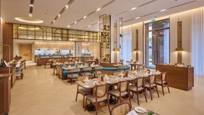 A spacious hotel dining area with multiple tables, chairs, and a central bar area. - Prachi Sarovar Premiere Bhubaneshwar (Bhubaneshwar)