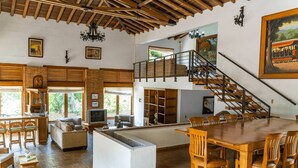 Un vaste espace de vie doté d’un haut plafond, d’une table à manger et d’un escalier menant à un niveau supérieur.