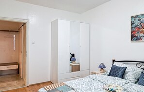 Ein Schlafzimmer mit Bett, Schrank, Nachttisch und einem Bild an der Wand.
