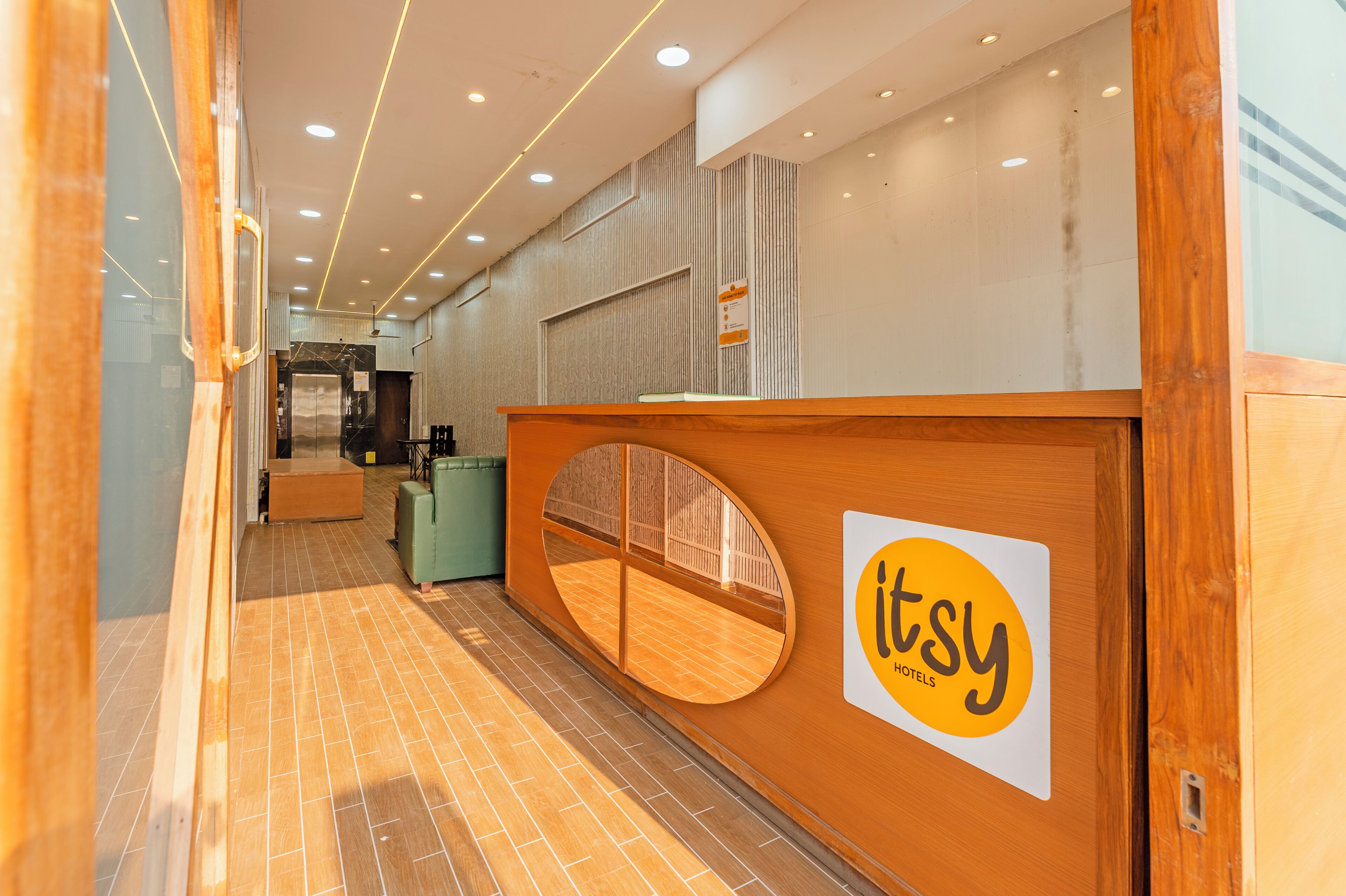 A reception area with a wooden reception desk, a glass partition, and a sign for Itsy Hotels.