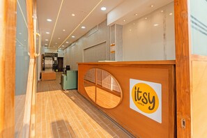 Et receptionområde med en træreception, en glasafskærmning og et skilt med Itsy Hotels.