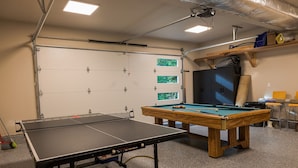 Une salle de billard équipée d’une table de billard américain, d’une table de snooker et d’un jeu de fléchettes.