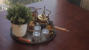 Une table sur laquelle se trouve un plateau avec un service à thé et une plante en pot, donnant sur une rivière et des bâtiments éloignés.