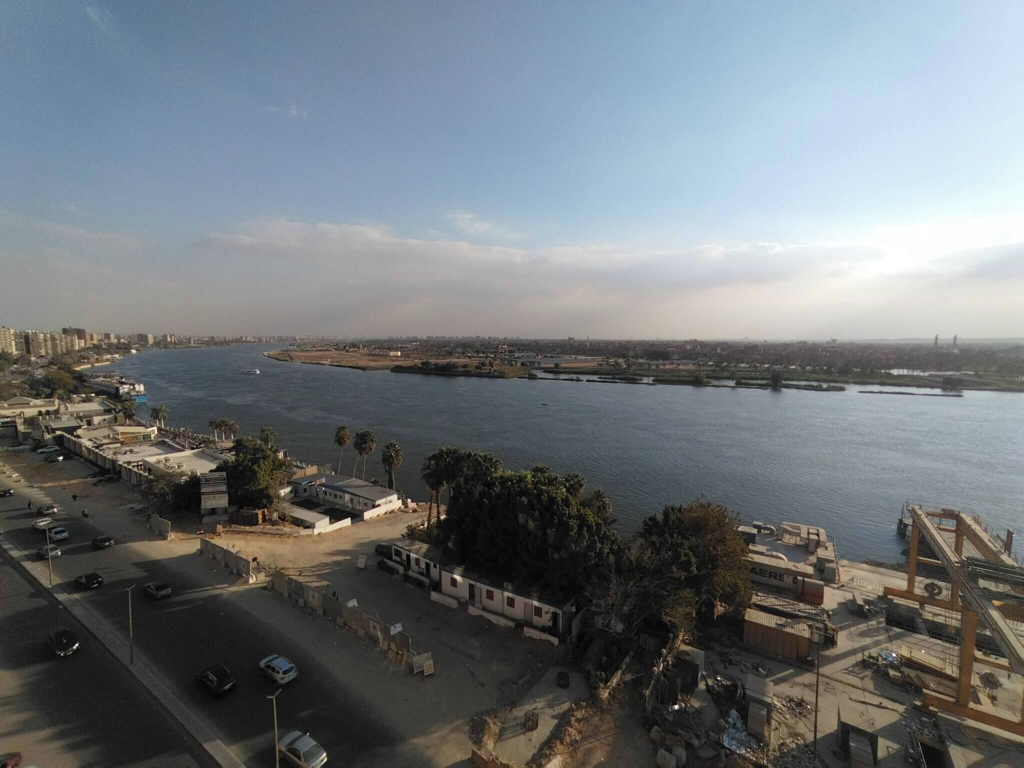 An aerial view of a coastal city with a river, buildings, and a clear sky.
