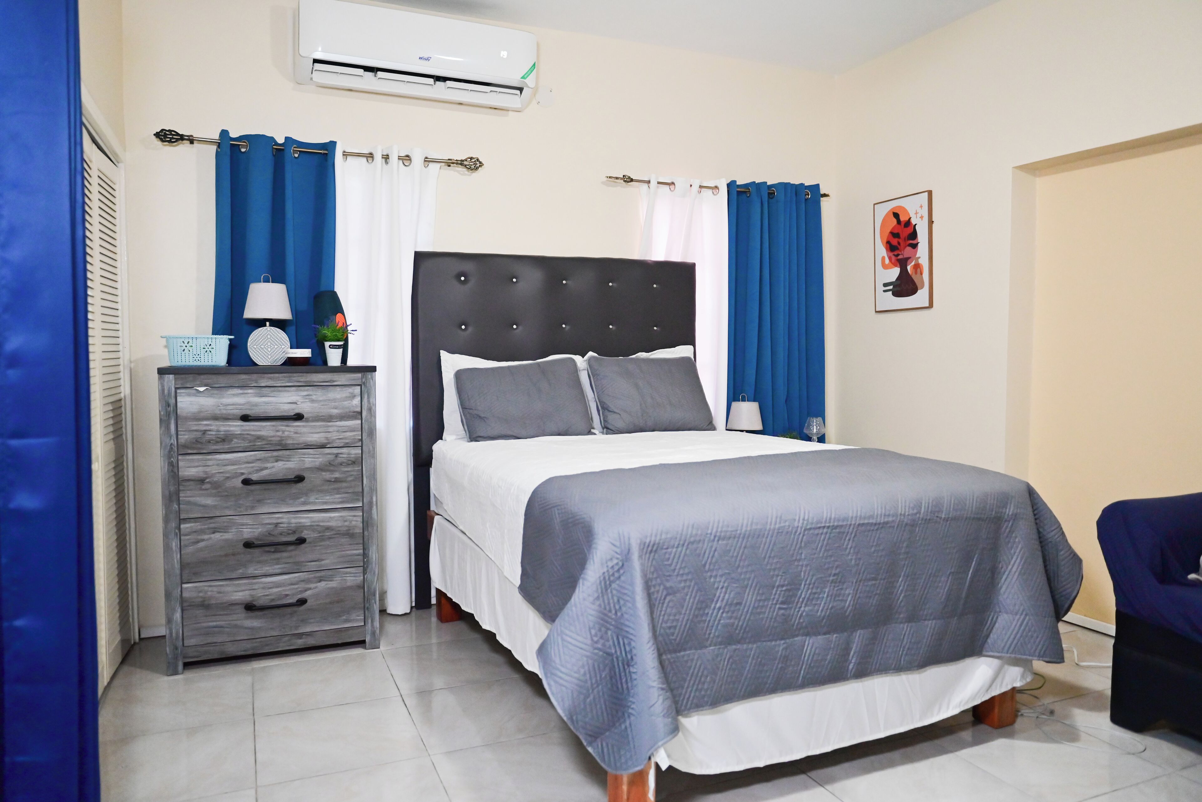 A neatly arranged bedroom with a bed, a dresser, and a chair.