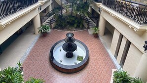 Ein Hotel-Atrium mit einer zentralen Fontäne, mehreren Balkonen und üppigem Grün.