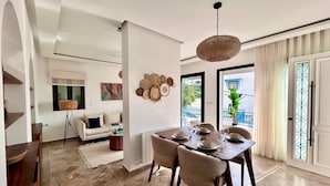 Zona pranzo con tavolo apparecchiato per quattro persone, una poltrona, una lampada da terra e un elemento decorativo a parete.