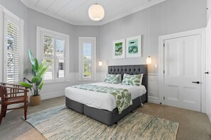 Ein Schlafzimmer mit einem Bett, einem Sessel, einer Pflanze und Bildern an der Wand.