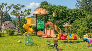 A playground with a yellow spiral slide, a green climbing wall, and various play structures.