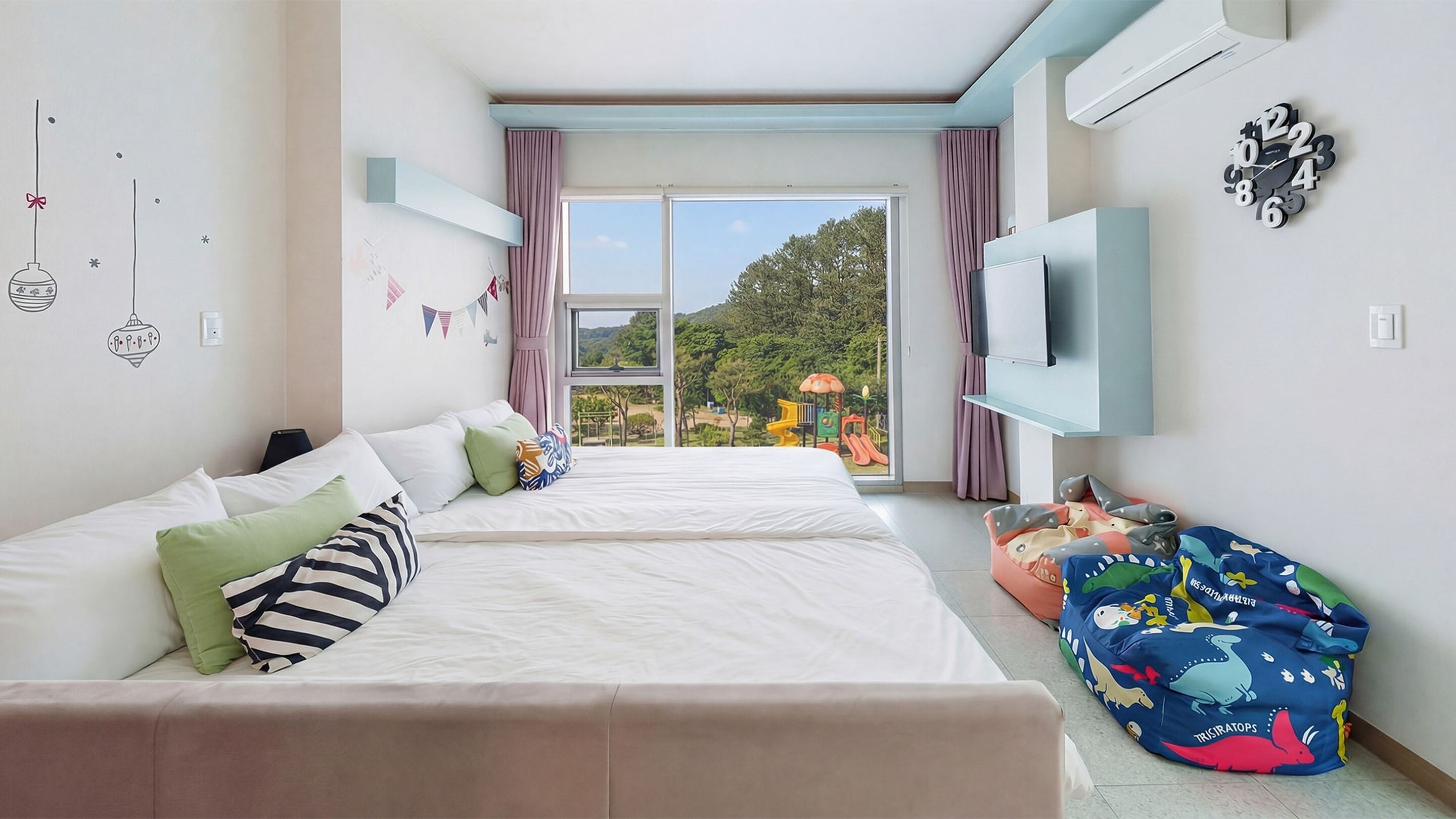 Una habitación de hotel moderna con dos camas, televisión y un ventanal grande con vista a un parque infantil.