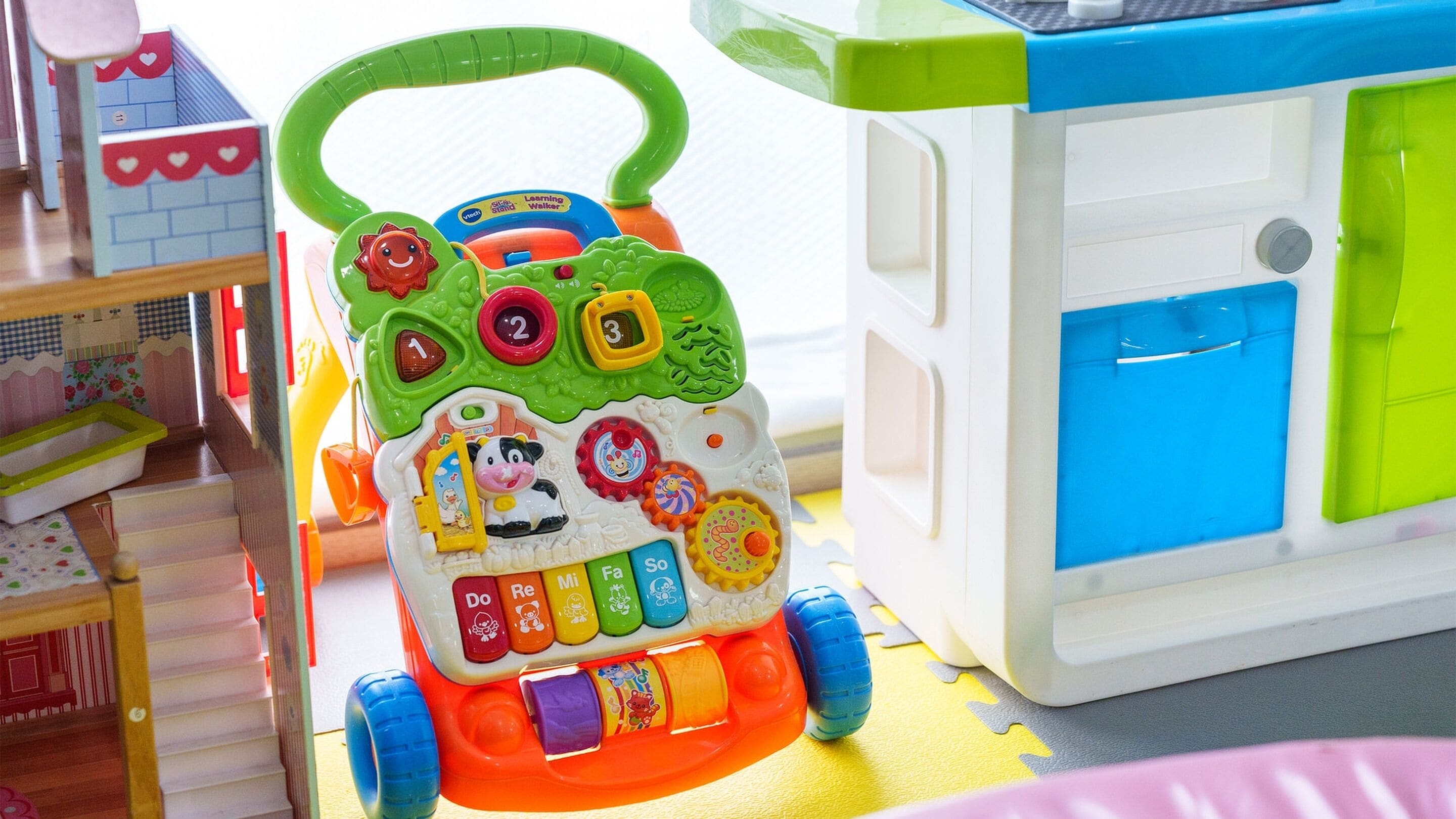 Un jouet éducatif pour enfants, doté d’une poignée verte, d’une base bleue et blanche, ainsi que de divers boutons et roues.