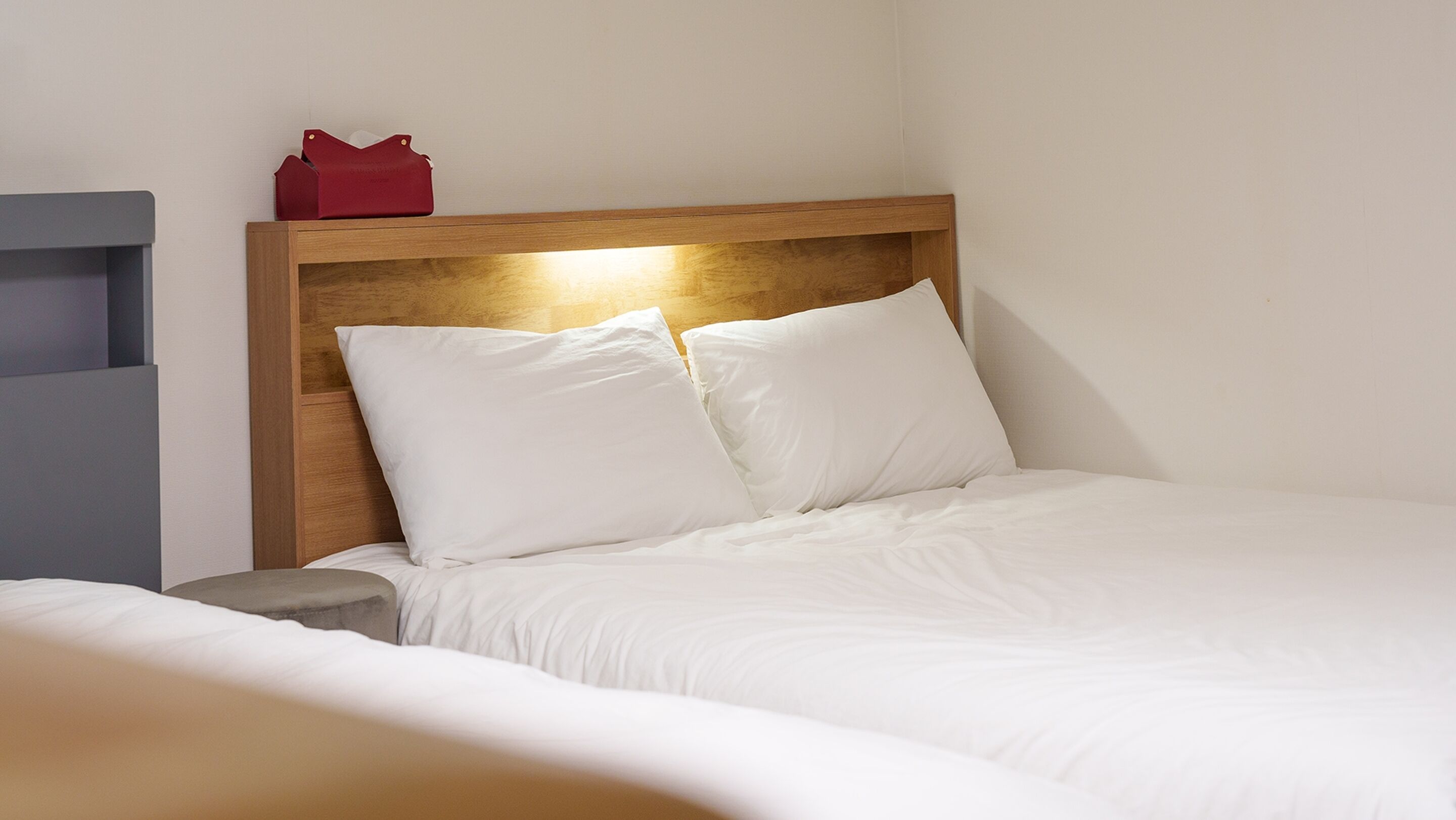 A neatly made bed with white bedding and a wooden headboard.