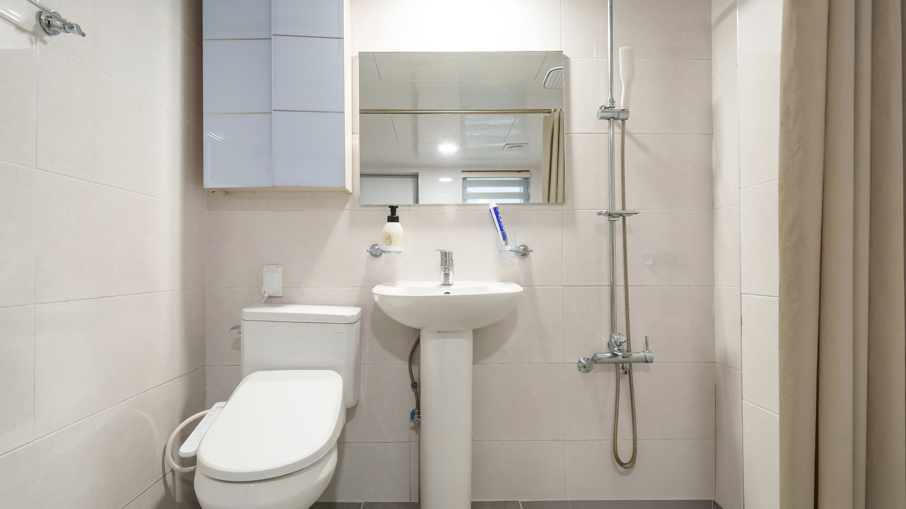 A bathroom with a toilet, sink, and shower.