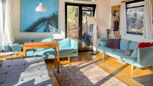 Un salon avec un canapé bleu clair, un pouf gris à motifs capitonnés, une table basse en bois et un tapis à motifs.