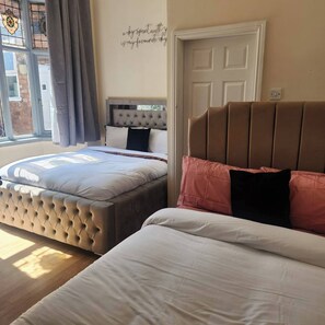 Een slaapkamer met twee bedden, een raam met gordijnen en een deur.