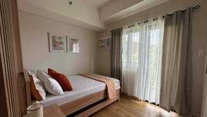 Una camera da letto con un letto di legno, un comodino, una finestra con tende e opere d'arte appese al muro.