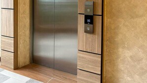 Un ascensore moderno con finiture metalliche, un pannello di controllo con display digitale e un design in legno.