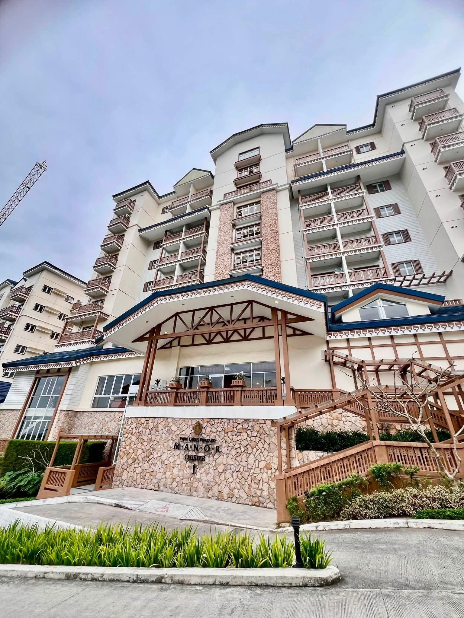A multi-story hotel with a stone facade, balconies, and a covered entrance.
