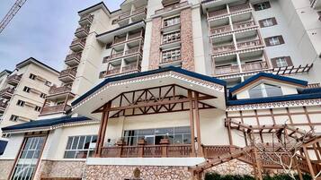 A multi-story hotel with a stone facade, balconies, and a covered entrance.