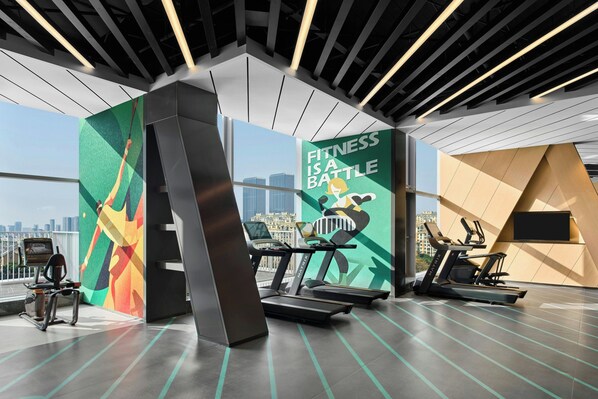 Ein modernes Fitnessstudio mit Laufbändern, einem motivierenden Zitat und Blick auf die Stadt.