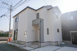 A modern two-story building with a flat roof, a front entrance with steps, and a small porch area. - 4BR Modern Home Near Kumamoto Airport by Restavio (Ozu)