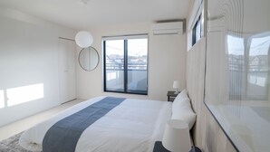 Ein modernes Hotelzimmer mit einem großen Bett, einem Nachttisch, einem Spiegel und einem Fenster mit Blick.