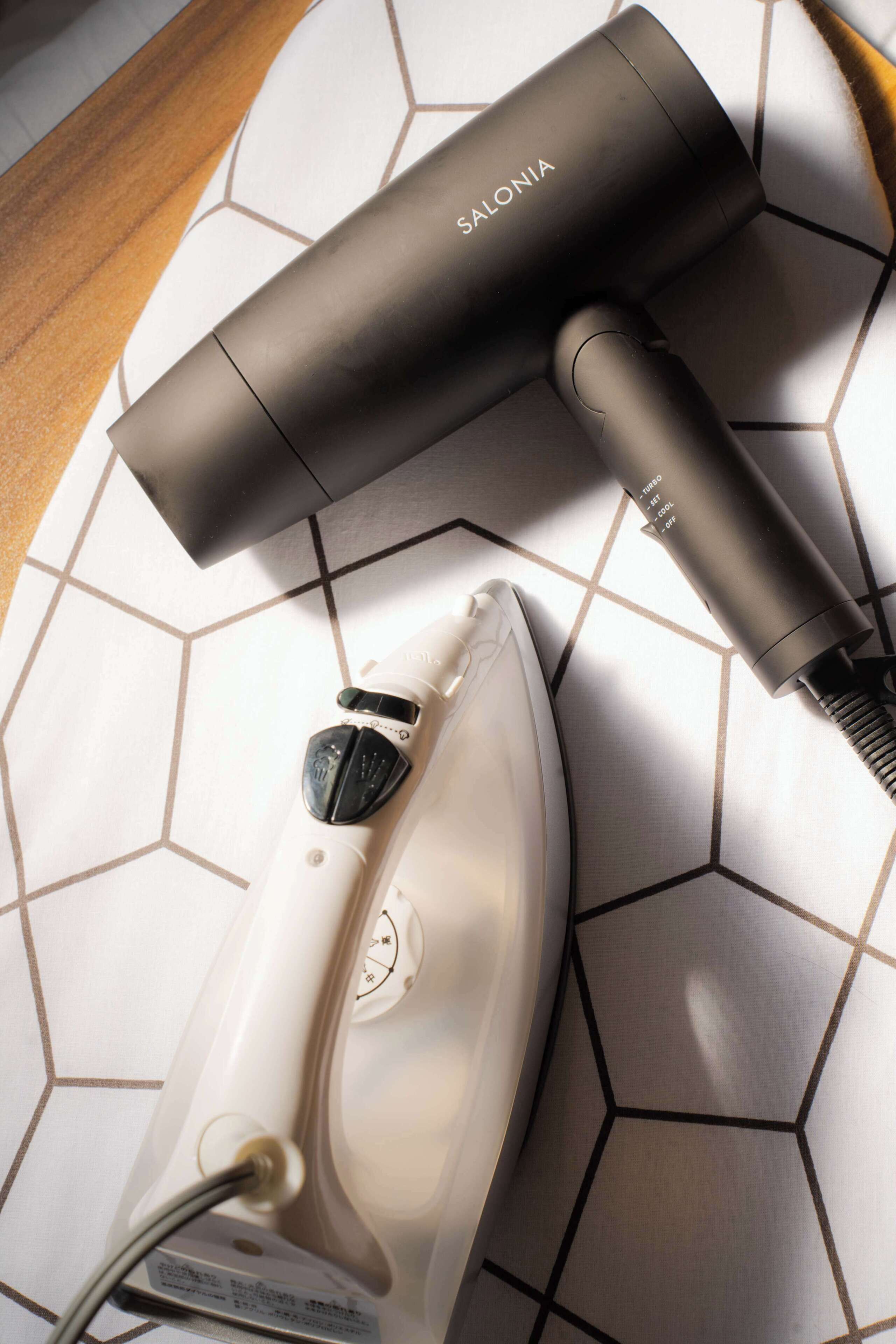 A hair dryer and an iron on a tiled floor.