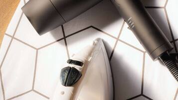 A hair dryer and an iron on a tiled floor.