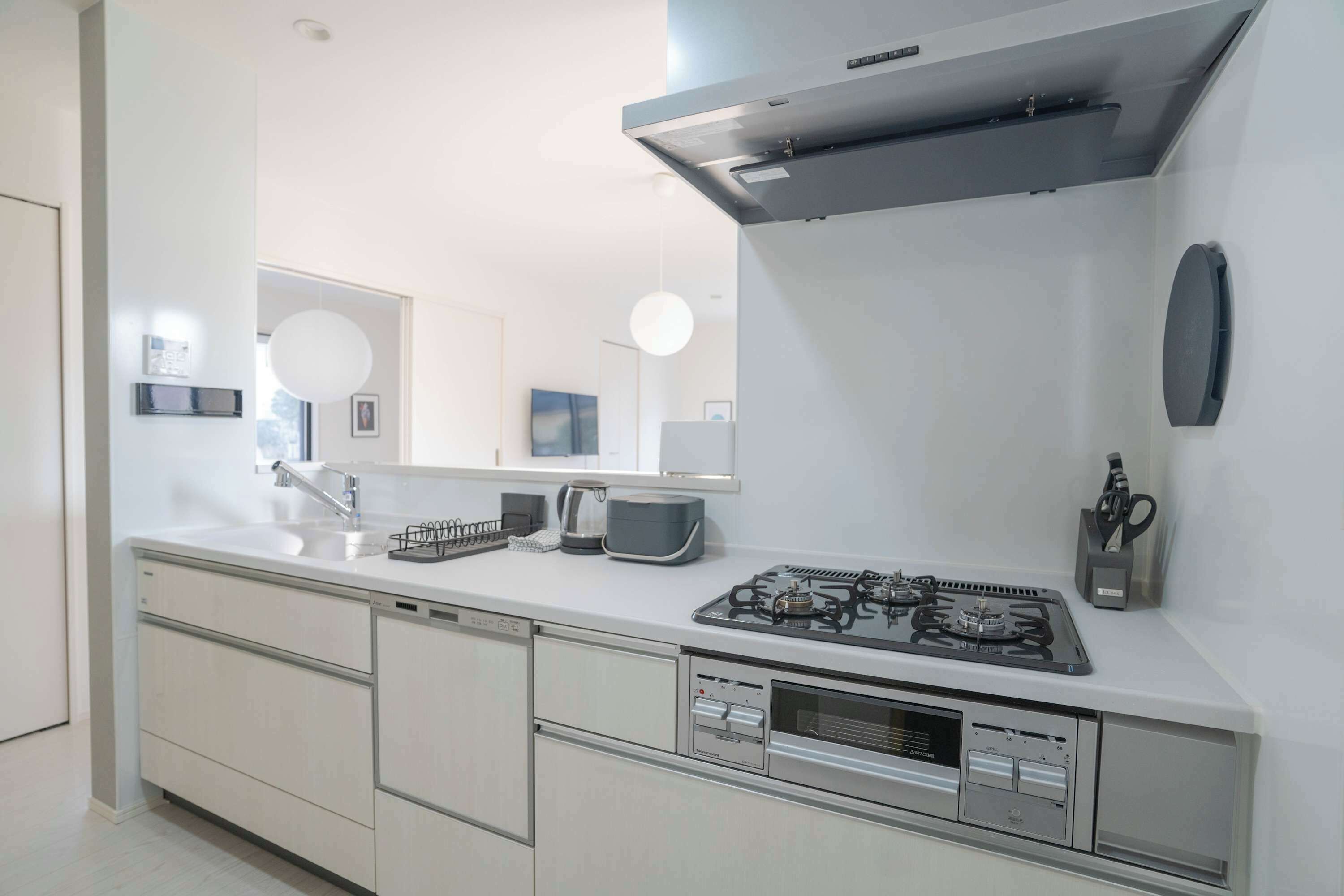 Una cocina moderna con estufa a gas, horno integrado, microondas y pileta.