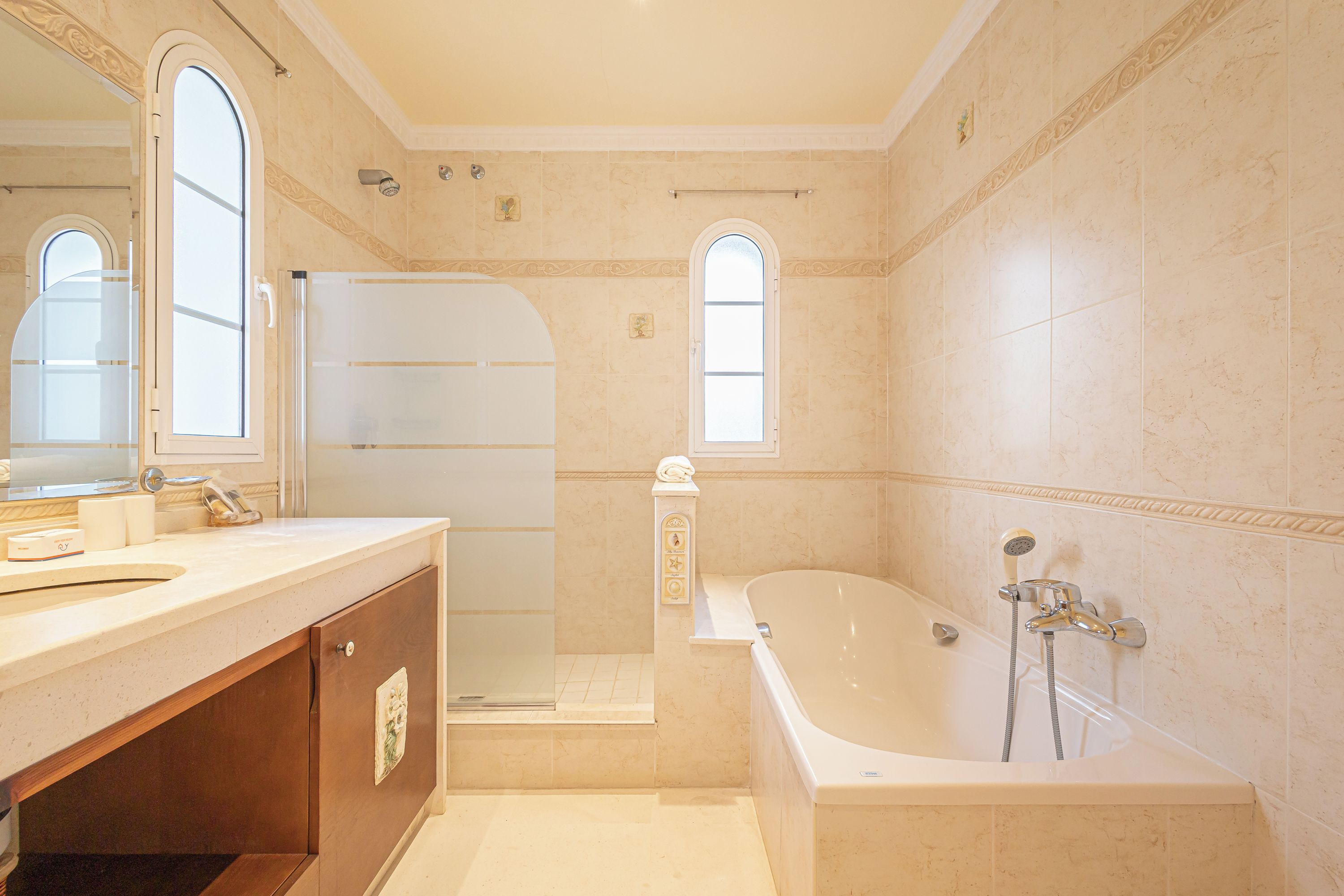 A bathroom with a bathtub, a shower, a sink, and a vanity.