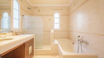 A bathroom with a bathtub, a shower, a sink, and a vanity.
