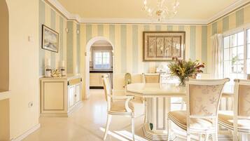 A dining area with striped walls, a chandelier, and a table with chairs.