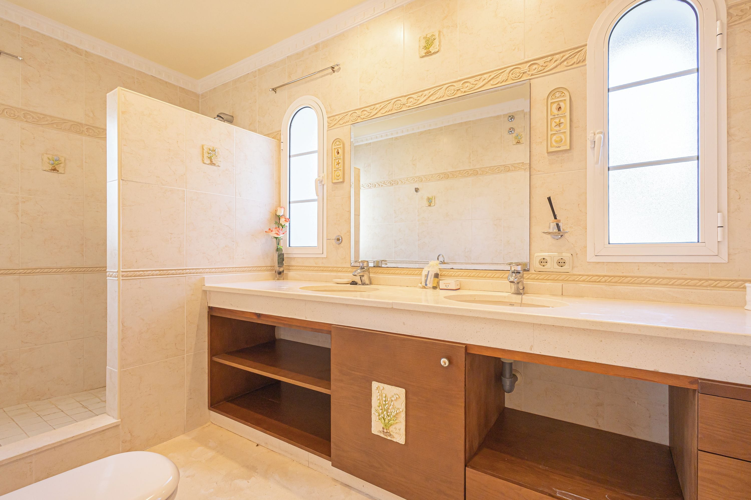 Een badkamer met een wastafelmeubel met dubbele wastafel, een toilet en een douchehoek.