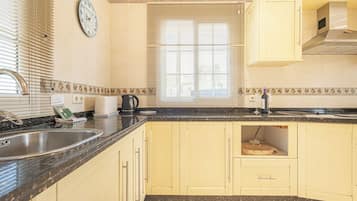 A kitchen with a sink, stove, and cabinets.
