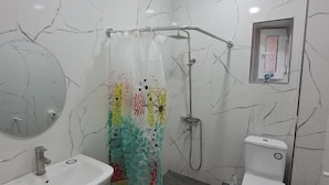 Un baño con ducha, inodoro, lavamanos y espejo.