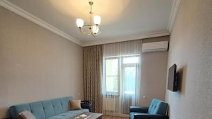 Una sala de estar con un sofá, dos sillones, una mesa de centro y una araña.