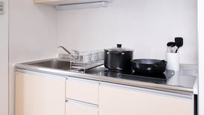 Een kleine keuken met een spoelbak, fornuis en kastjes.