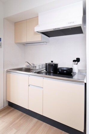 A compact kitchen with a sink, stove, and cabinets. - The Peak Shinsaibashi Elite (Osaka)