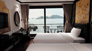 A hotel room with two beds, a desk, a chair, a TV, and a view of the sea and boats. - HALORA NOVA LUXURY CRUISE (Bai Chay)